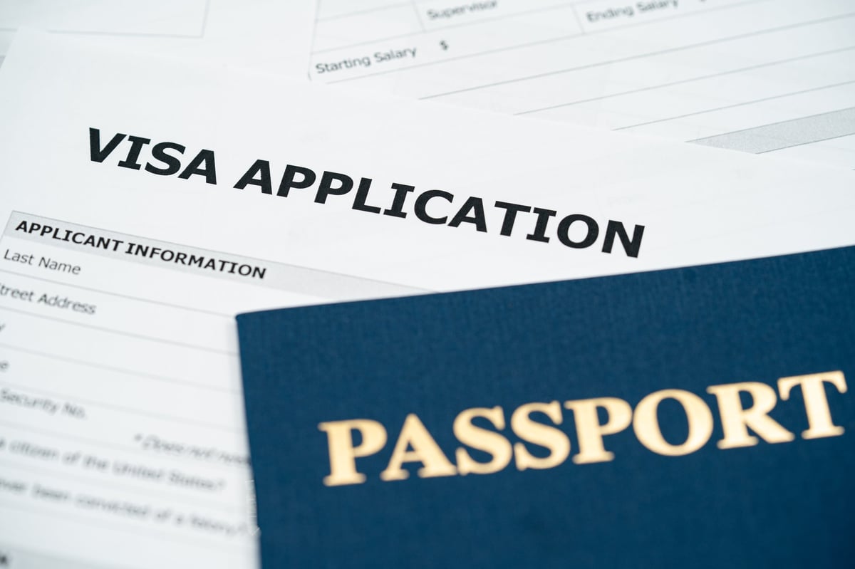 Pasaporte y formulario de solicitud de visa china sobre escritorio profesional, representando el complejo trámite del sistema COVA en 2026
